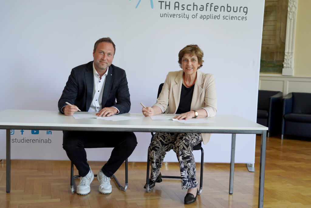 Christopher Franz (Vorstand Caritasverband Aschaffenburg – Stadt und Landkreis e.V.) und Prof. Dr. Eva-Maria Beck-Meuth (Präsidentin der TH Aschaffenburg) bei der Vertragsunterzeichnung im Hocksaal