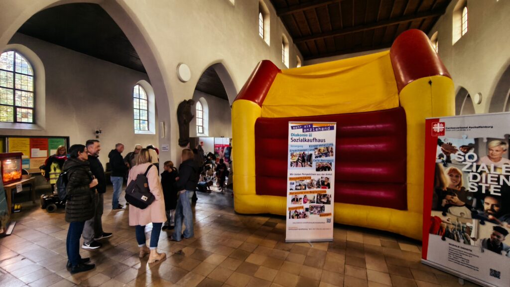 Menchenmenge in der Kirche St. Agatha, im Hintergrund eine Hüpfburg, auf der Kinder hüpfen